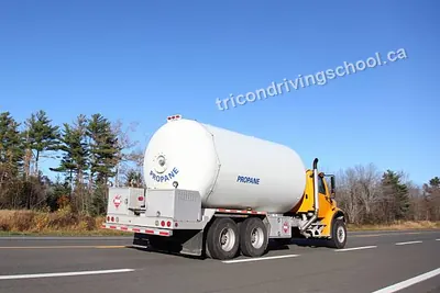 Propane delivery truck with a white tank on a highway