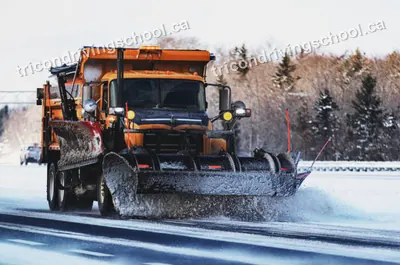 Orange snow plow truck clearing a snowy highway