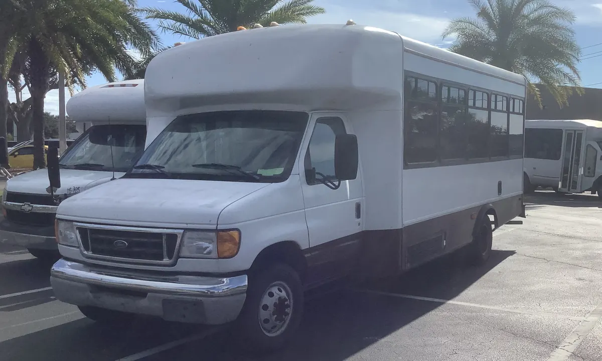 White small bus with a row of passenger windows, parked in a car park