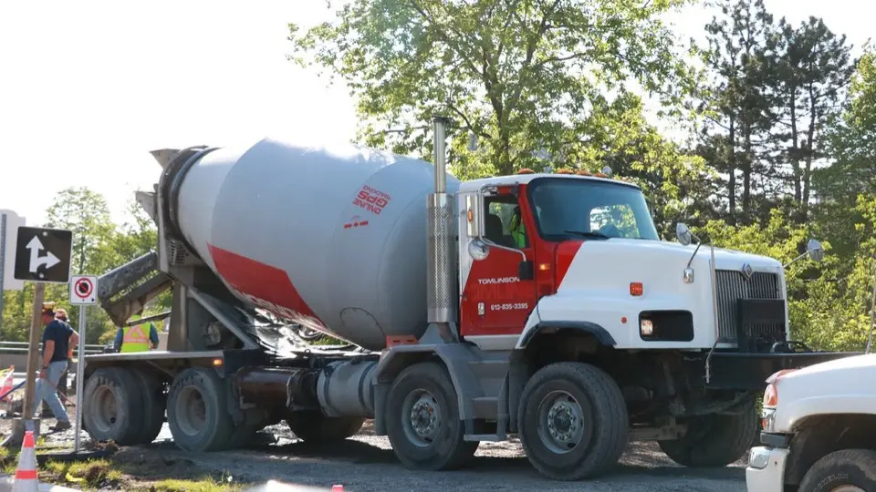 A four-axle cement mixer truck with its drum loaded at a construction site